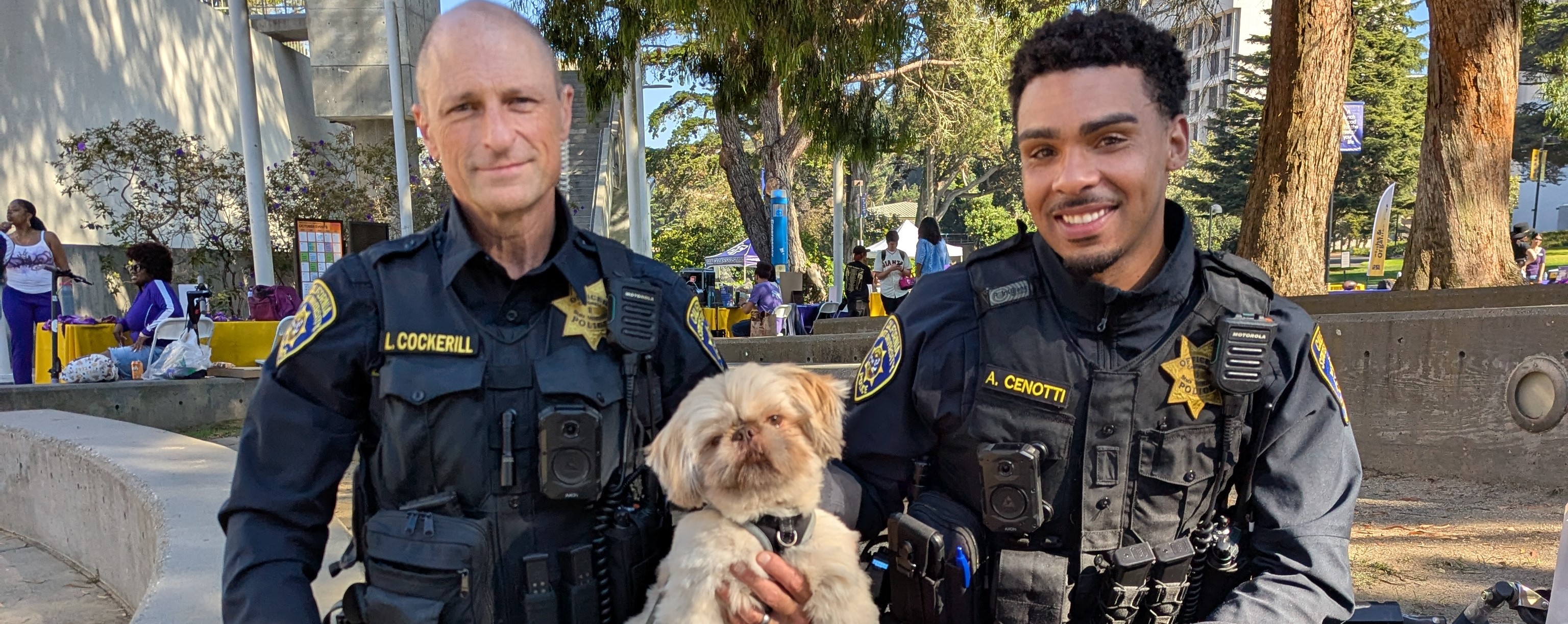 UPD officers at the Discover SF State event sitting with a community member's dog