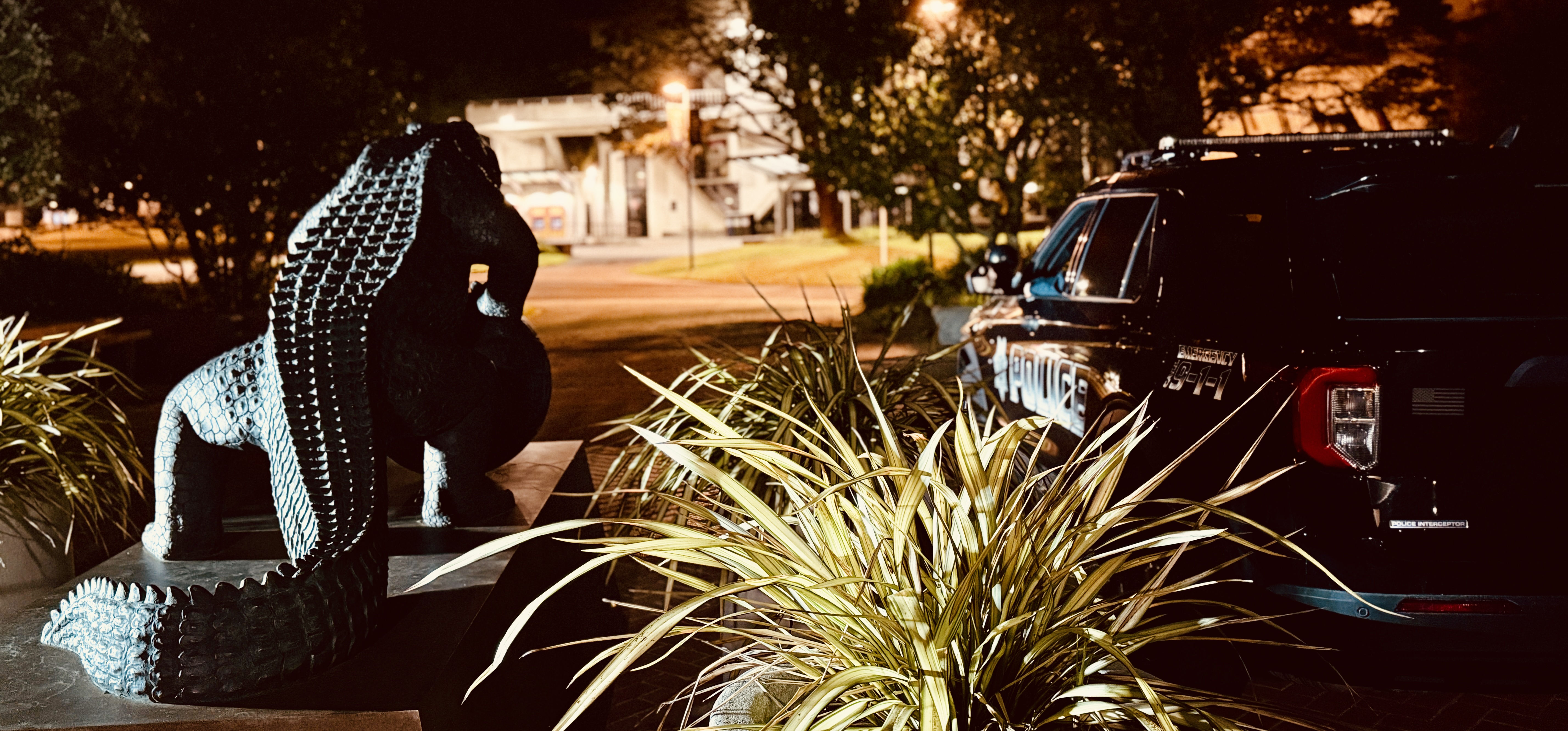 Image of a UPD police vehicle parked next to the SFSU Gator statue near the gymnasium.