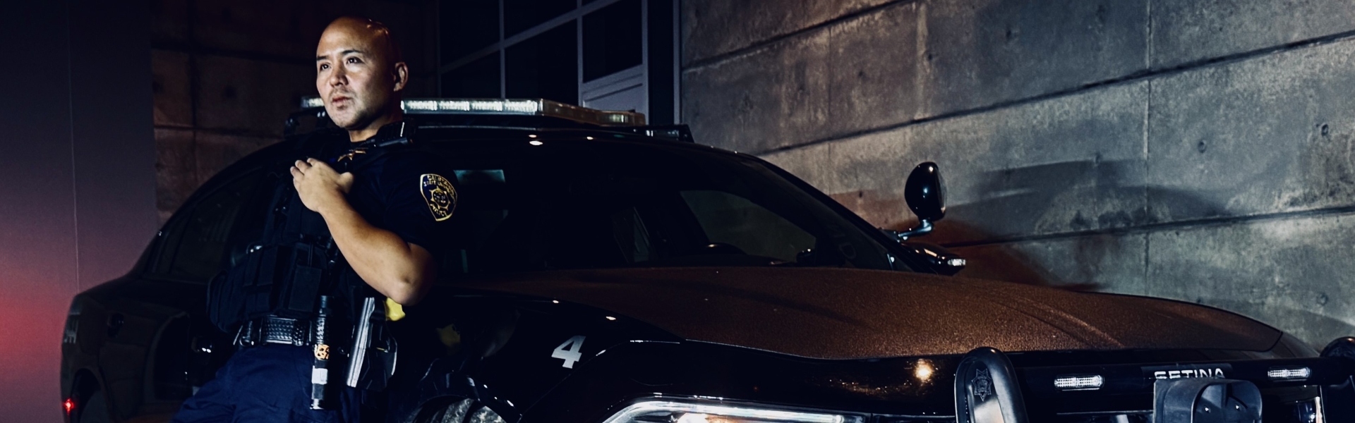 Image of an officer leaning against a police vehicle